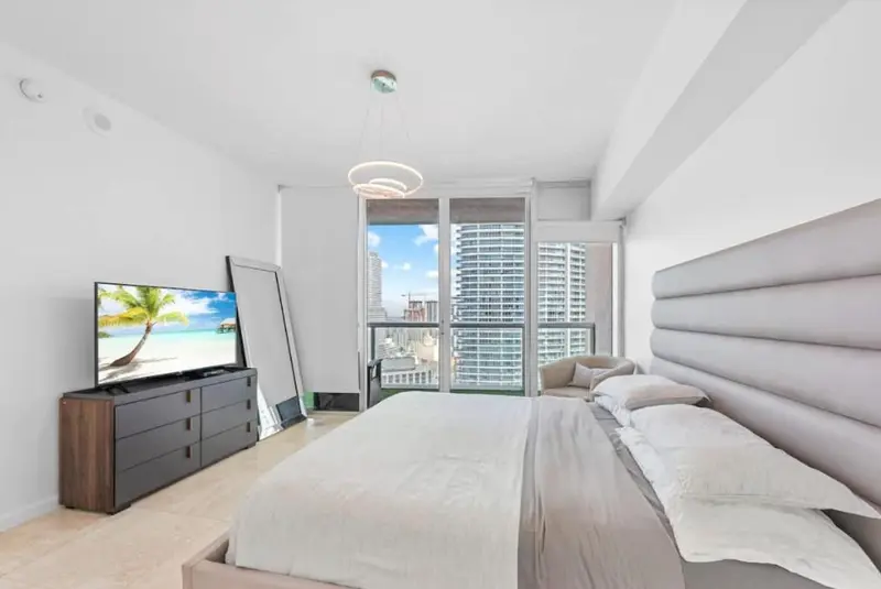 Une chambre lumineuse avec un grand lit et une vue sur la ville.
