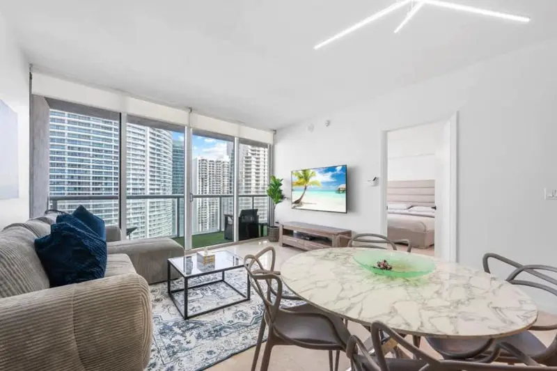 Un salon lumineux avec un coin repas donnant sur une vue urbaine.