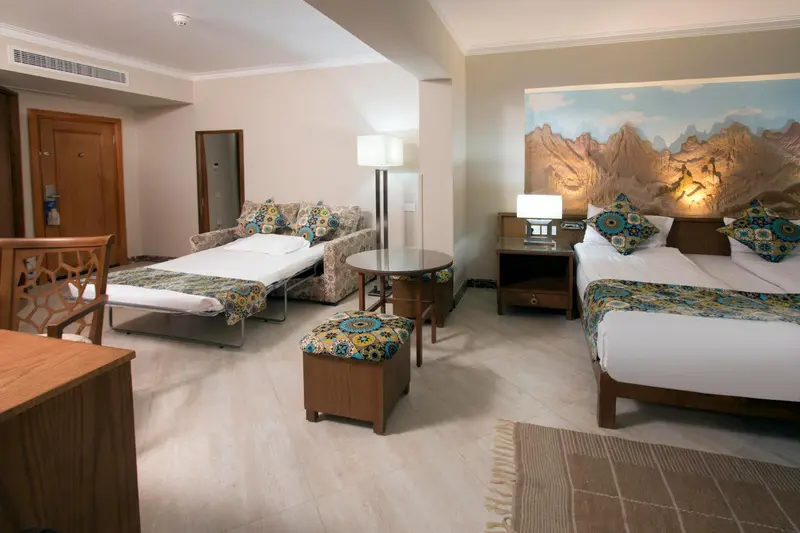Une chambre lumineuse avec deux lits et un canapé convertible.