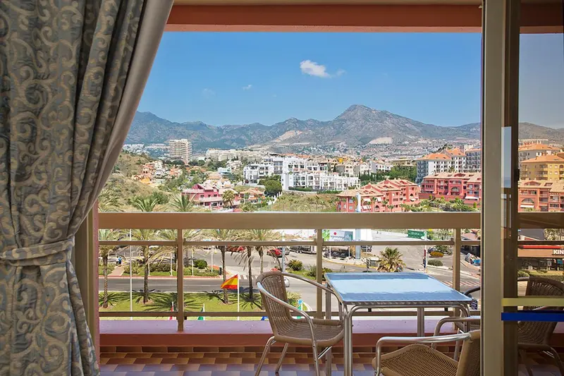 Vue sur une ville côtière et des montagnes depuis un balcon.