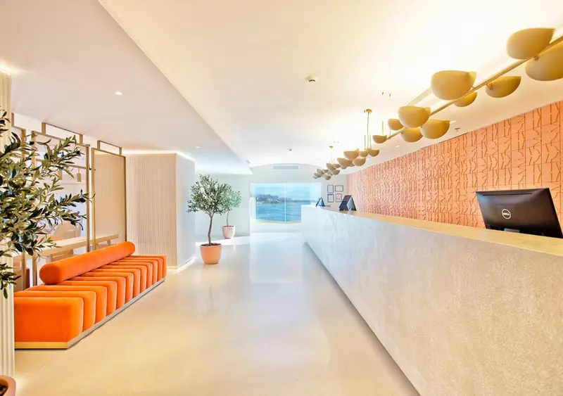 Un hall d'accueil lumineux avec un comptoir et un canapé orange.