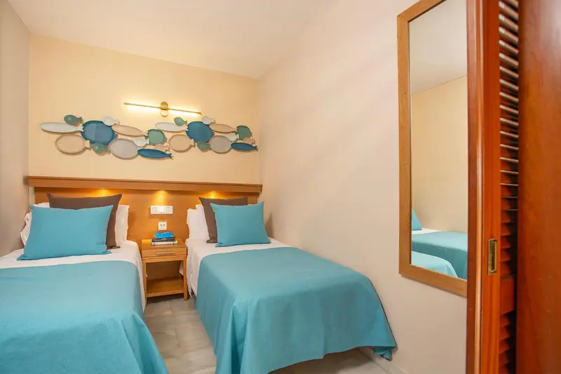 Une chambre lumineuse avec deux lits simples et une décoration murale abstraite.