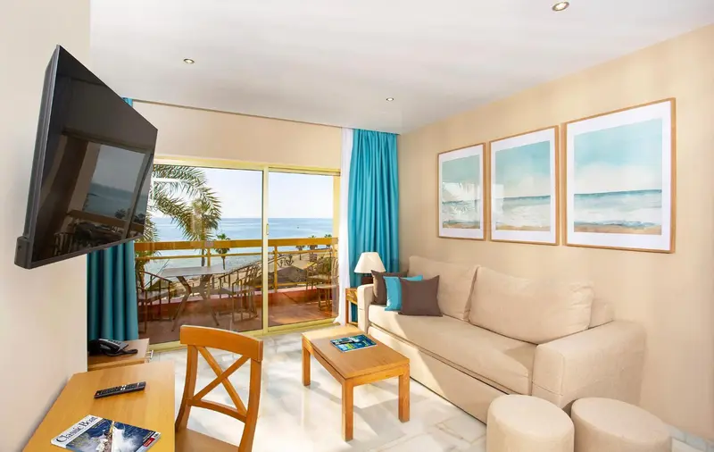 Espace de vie lumineux avec canapé et vue sur la mer depuis un balcon.