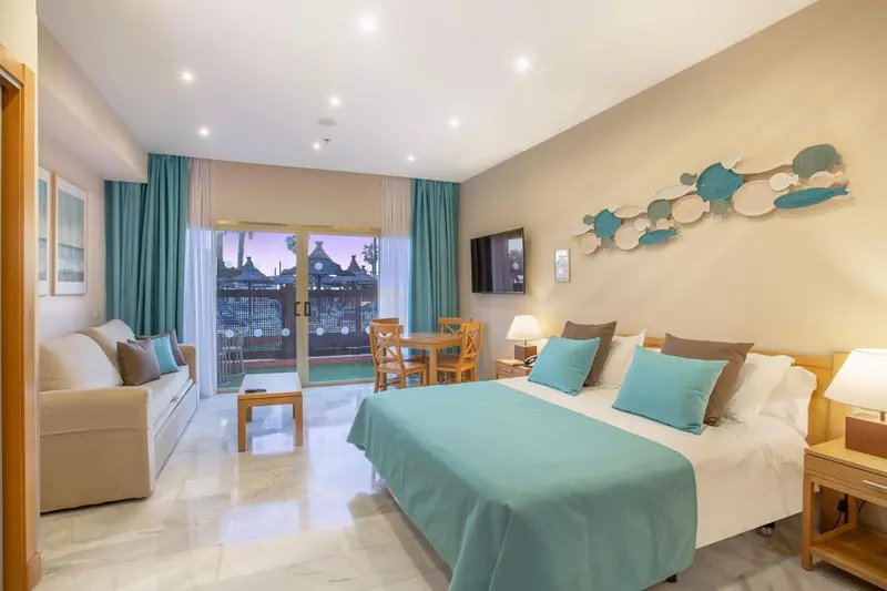 Une chambre lumineuse avec un canapé, un lit et un accès à une terrasse.