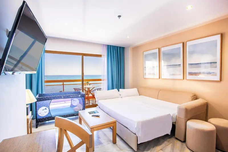 Une chambre lumineuse avec un lit et un canapé face à une vue sur la mer.