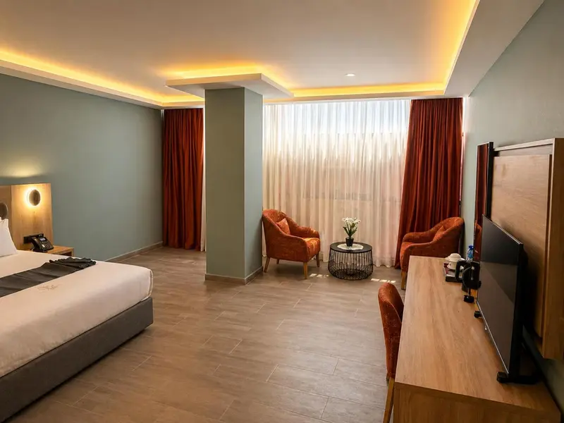 Une chambre lumineuse avec un lit, des fauteuils et un bureau.