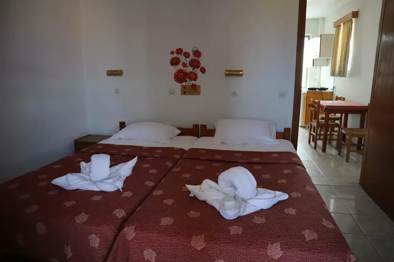 Une chambre avec deux lits simples et un coin repas attenant.
