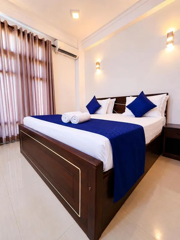 Une chambre avec un grand lit recouvert d'une courtepointe bleue et de coussins.