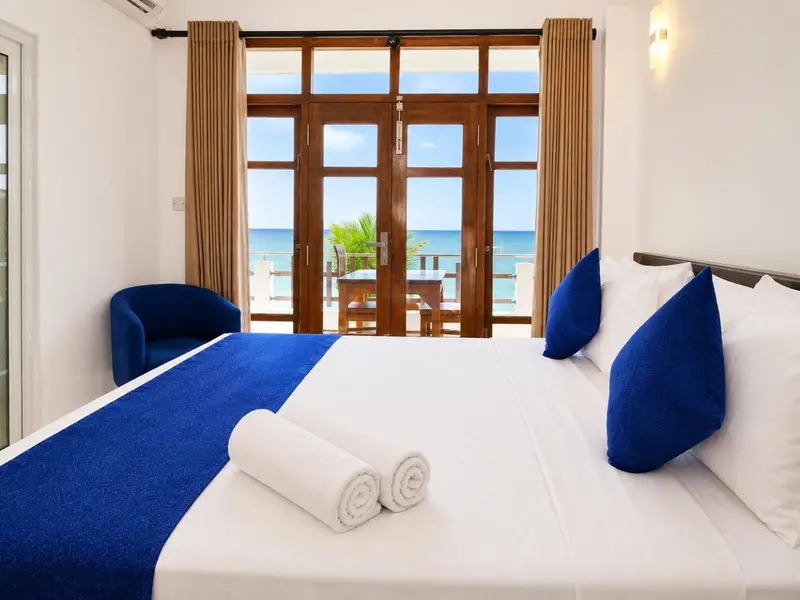 Une chambre lumineuse avec un lit fait et vue sur la mer.