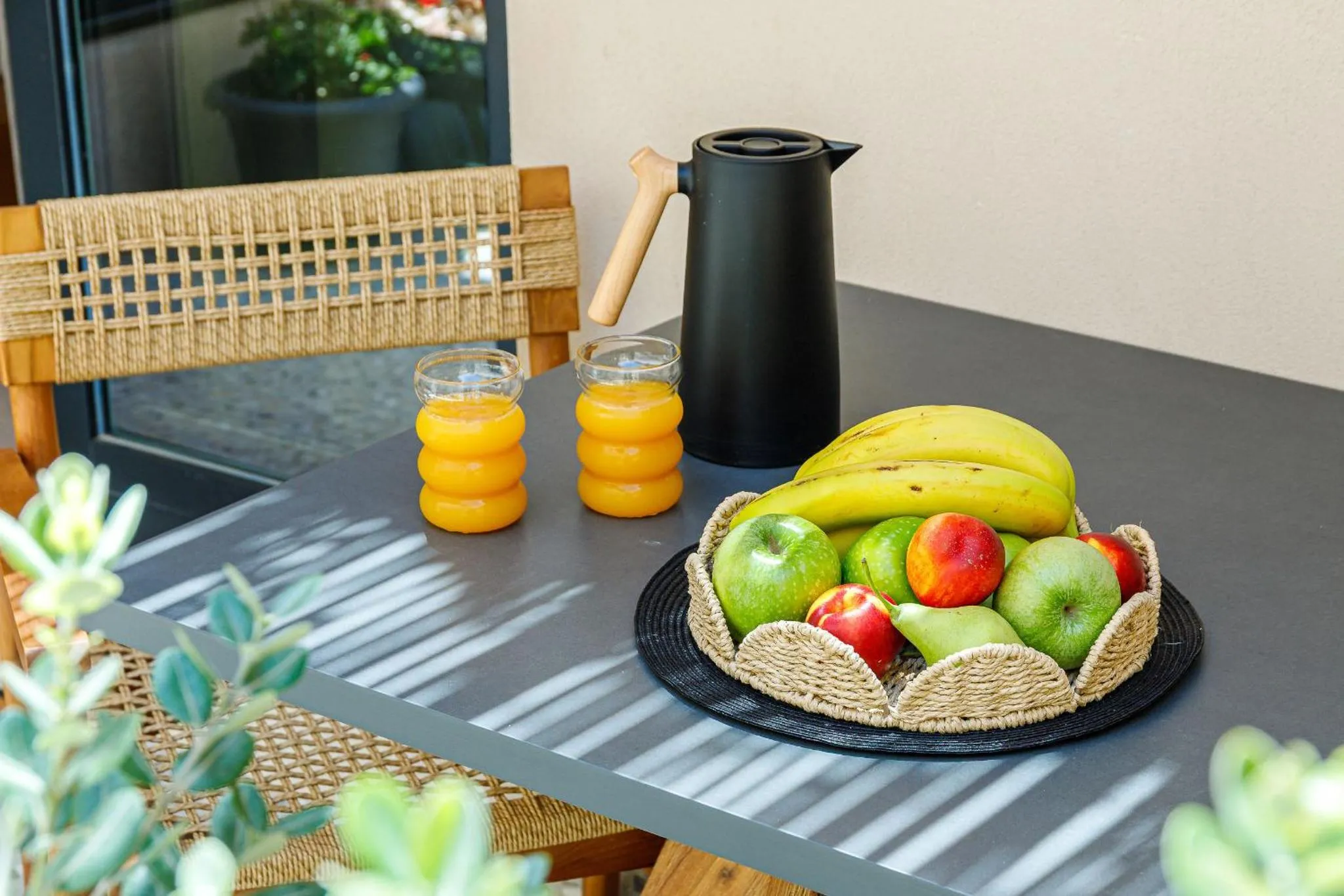 Une table avec des fruits et des boissons sur une terrasse.