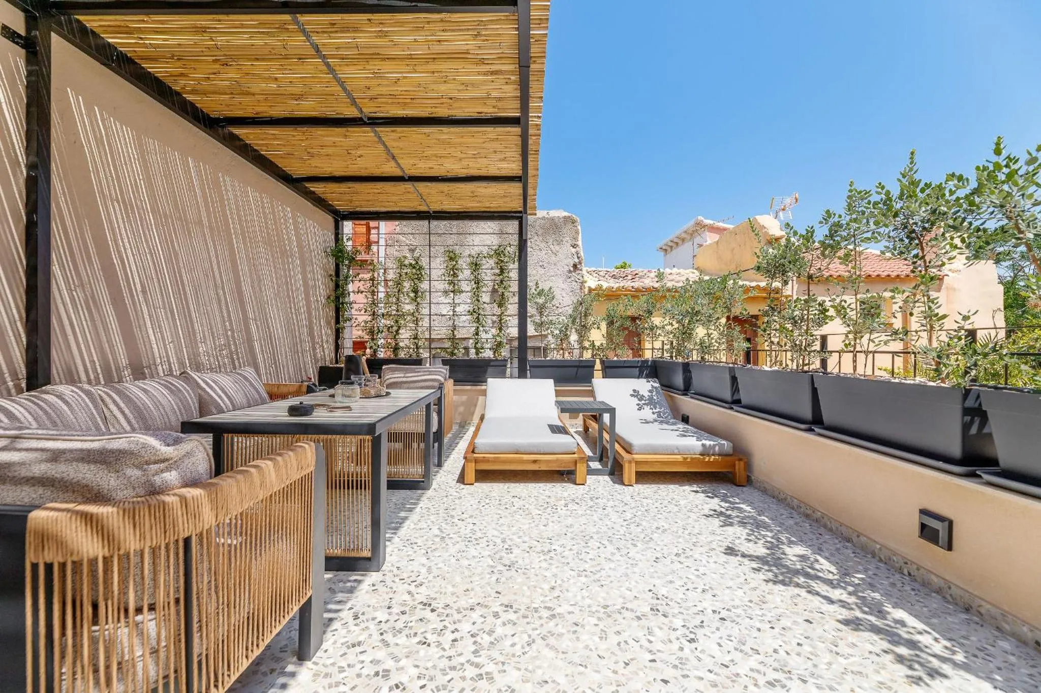 Espace de détente extérieur avec mobilier de jardin et pergola ombragée.