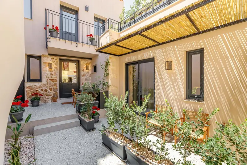 Façade d'un bâtiment avec un patio fleuri et une terrasse ombragée.