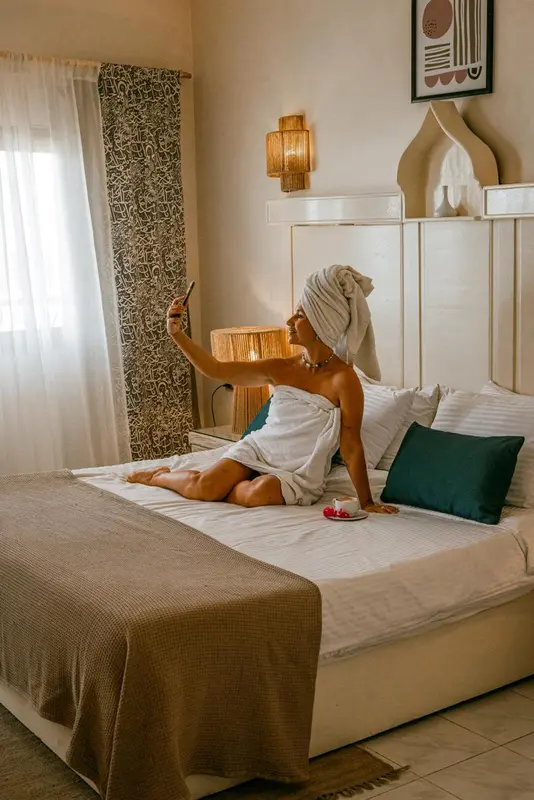 Une femme enveloppée dans une serviette est assise sur un lit dans une chambre décorée.