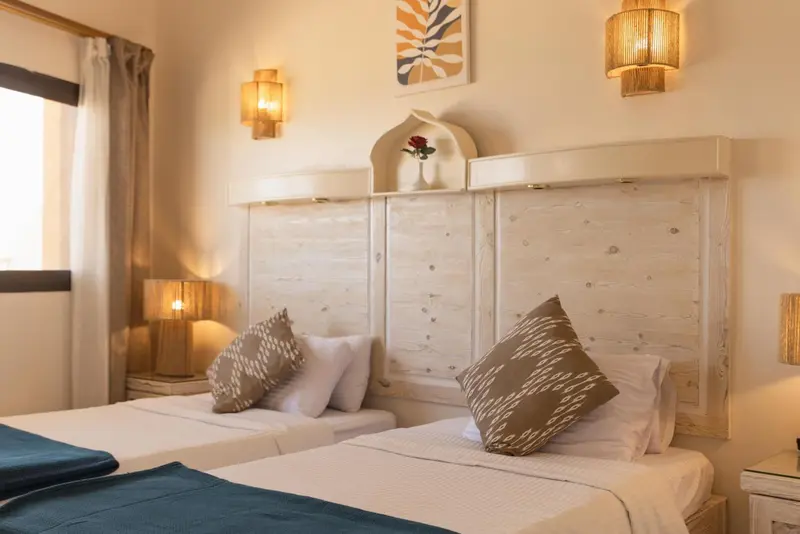 Une chambre lumineuse avec deux lits simples et une décoration murale.