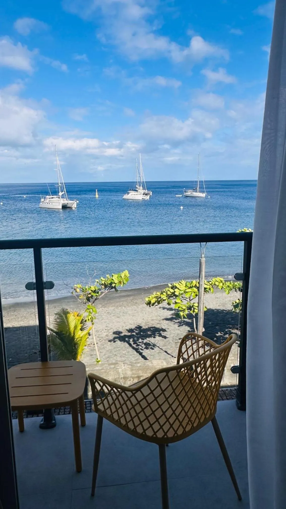 Vue sur la mer depuis une terrasse avec mobilier en rotin.