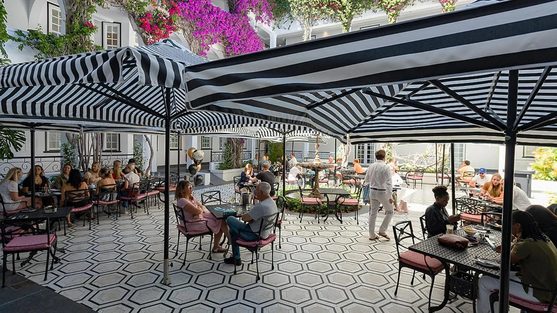 Une terrasse ombragée avec des tables et des chaises accueillant des clients.