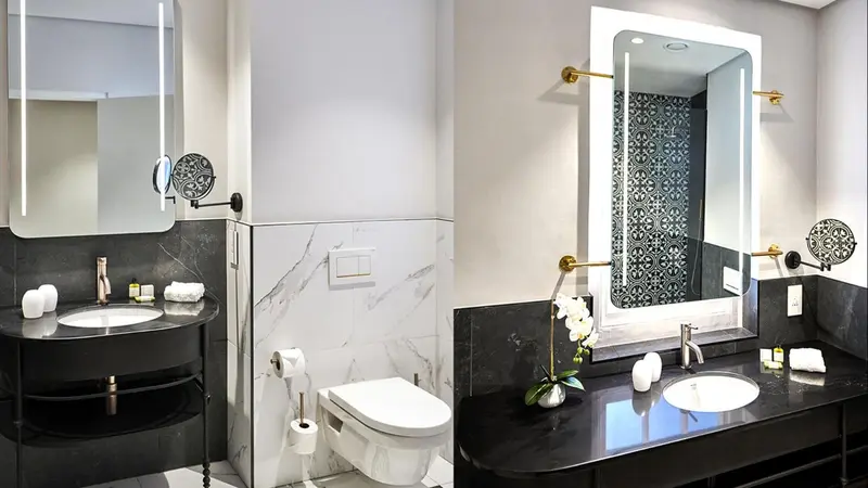 Une salle de bain moderne avec un lavabo noir et un grand miroir lumineux.