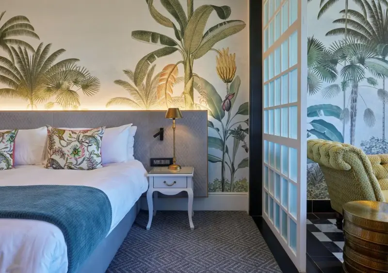 Une chambre d'hotel avec un lit recouvert d'une couverture bleue et des oreillers.