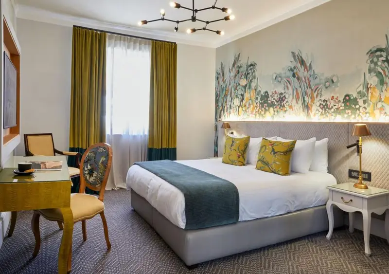Une chambre d'hôtel lumineuse avec un lit double et un coin bureau.