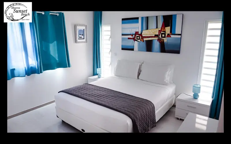Une chambre lumineuse avec un grand lit et des rideaux turquoise.