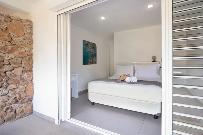 Une chambre lumineuse s'ouvre sur une terrasse ombragée.
