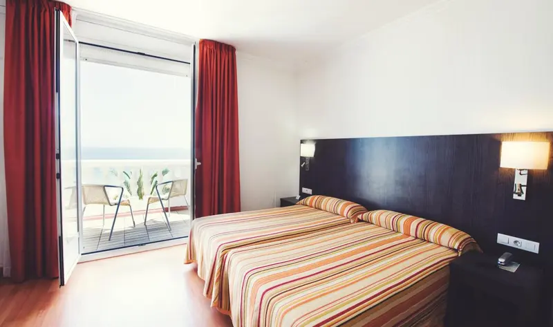 Une chambre lumineuse s'ouvre sur une terrasse avec vue sur la mer.