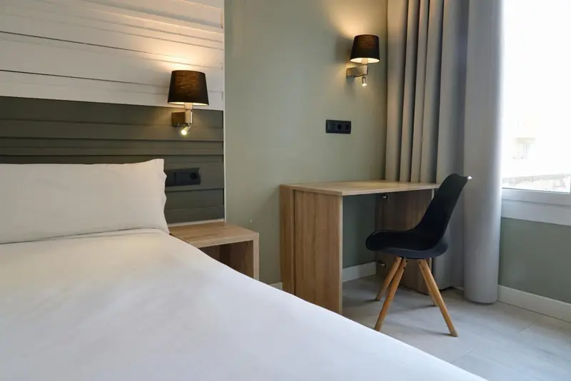 Une chambre lumineuse avec un lit simple et un bureau en bois.