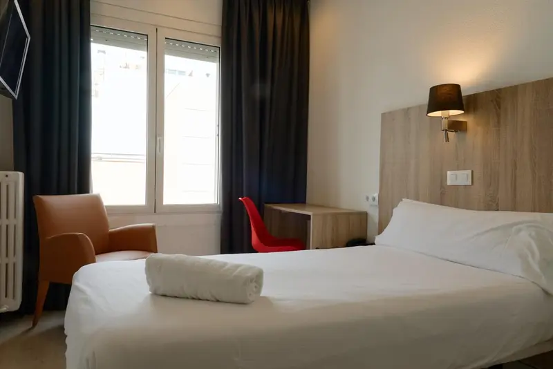 Une chambre lumineuse avec un lit simple et un fauteuil.