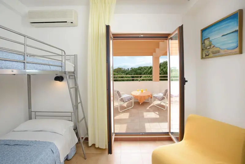 Une chambre lumineuse s'ouvre sur une terrasse avec vue sur la végétation.