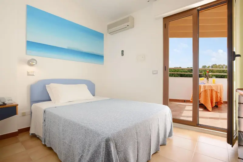 Une chambre lumineuse s'ouvre sur une terrasse avec table et chaises.