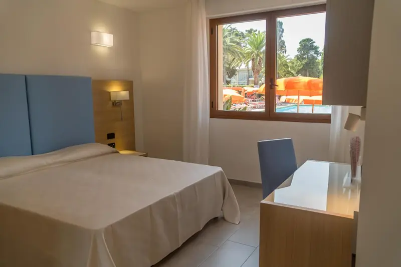 Chambre lumineuse avec un lit simple et un bureau près d'une fenêtre.