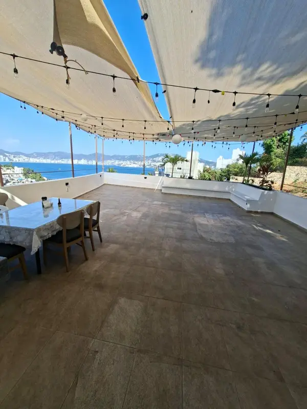 Terrasse ombragée avec tables et vue sur la mer.