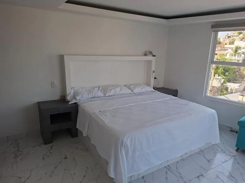 Une chambre lumineuse avec un grand lit recouvert de draps blancs.