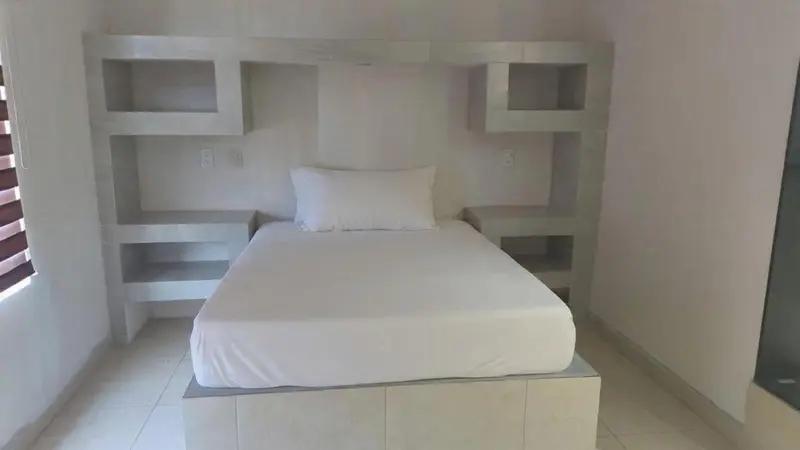Une chambre lumineuse avec un lit simple et des étagères murales.