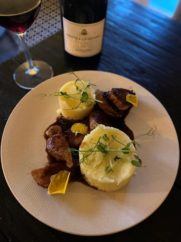 Assiette de viande accompagnée de purée et d'une décoration végétale.