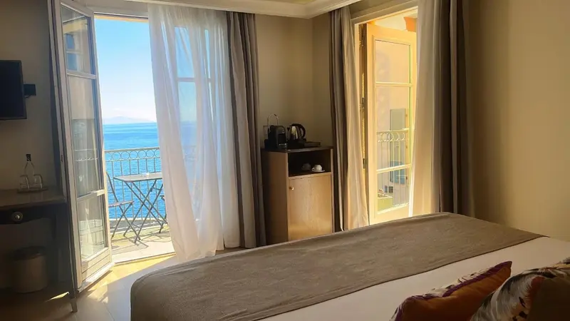 Une chambre lumineuse s'ouvre sur une terrasse avec vue sur la mer.