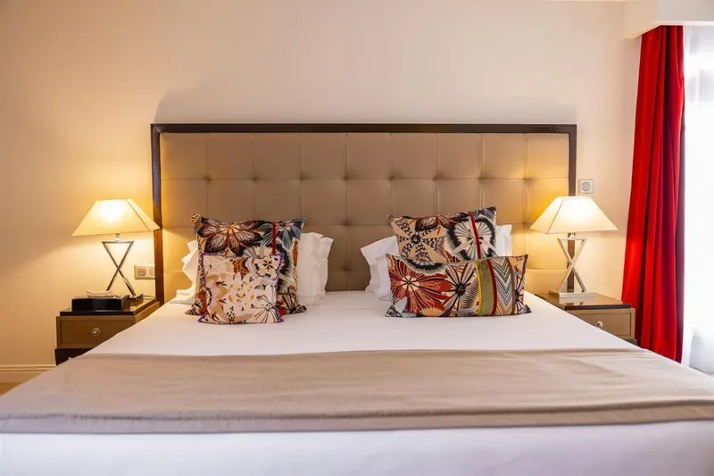 Un lit double avec une tête de lit rembourrée et des oreillers décoratifs.