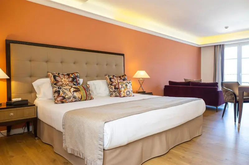 Une chambre lumineuse avec un grand lit et un coin salon.