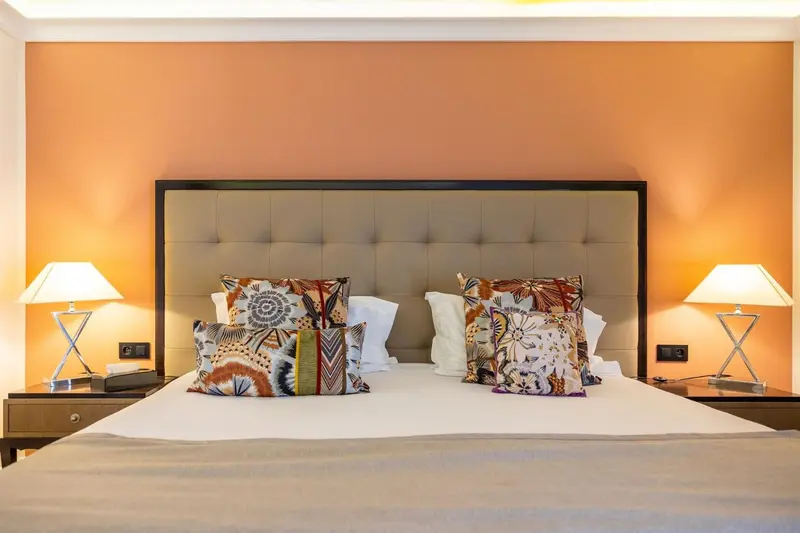 Un lit double avec une tête de lit rembourrée et plusieurs oreillers décoratifs.
