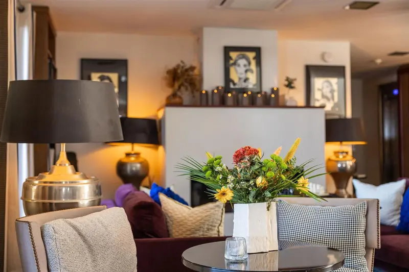 Un coin salon chaleureux avec des fauteuils confortables et des arrangements floraux.