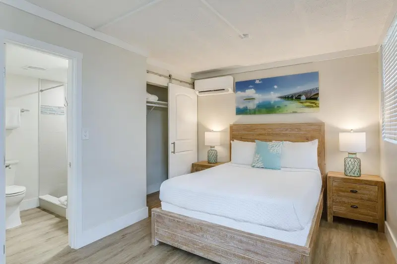 Une chambre lumineuse avec un grand lit et un accès à une salle de bain.