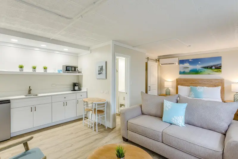 Espace de vie lumineux avec cuisine équipée et canapé gris.