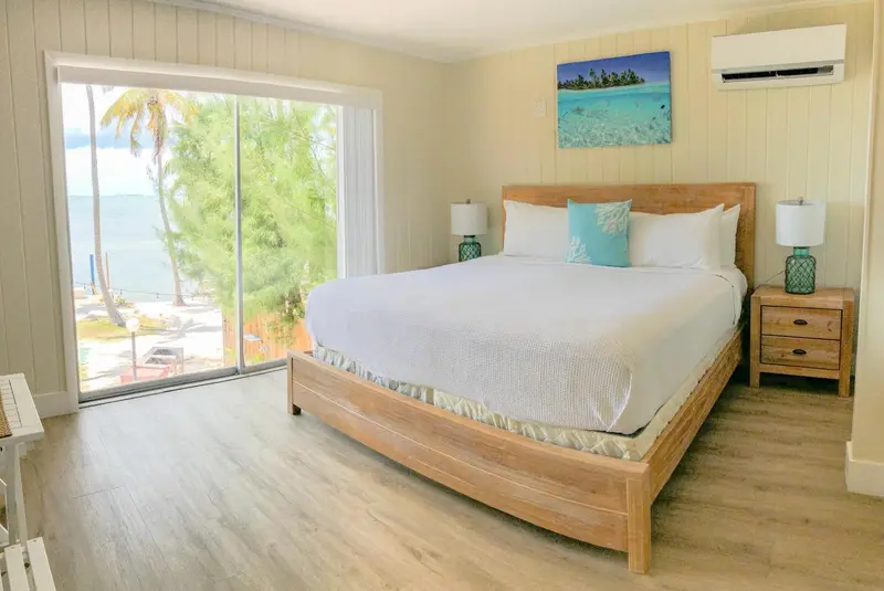 Une chambre lumineuse avec un grand lit face à une baie vitrée.