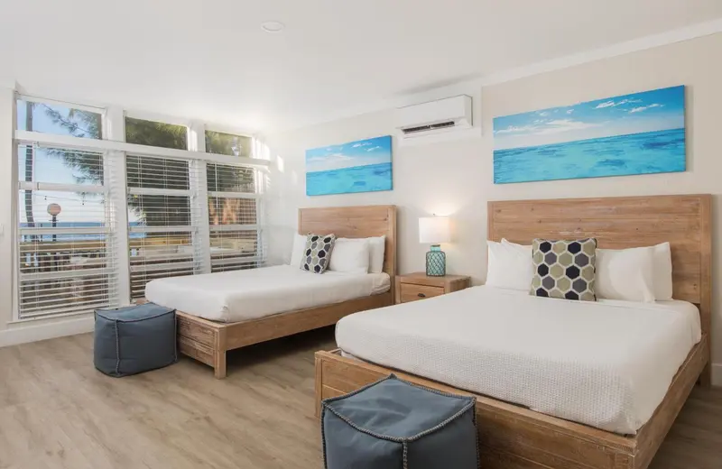 Chambre lumineuse avec deux lits simples et vue sur la mer.