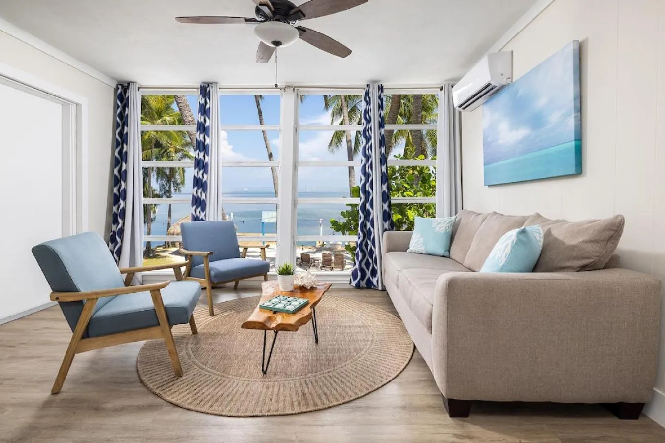 Espace de détente lumineux avec canapé et fauteuils face à une vue sur la mer.