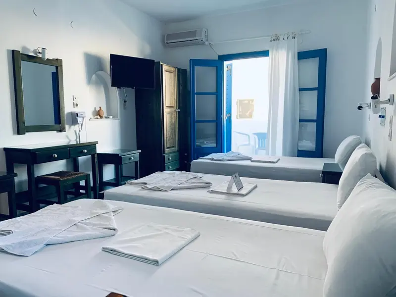 Une chambre lumineuse avec deux lits et une vue sur la mer.