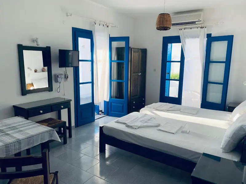Une chambre lumineuse avec un lit fait et un coin repas près de la fenêtre.