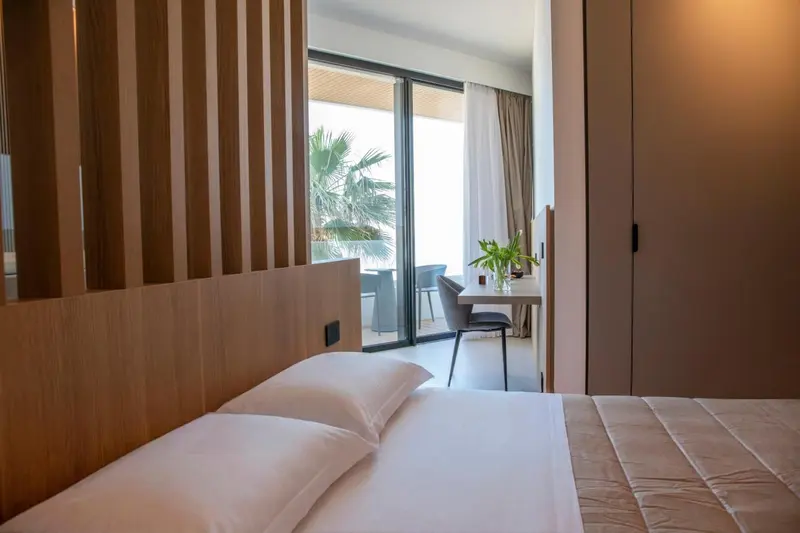 Une chambre lumineuse avec un lit et un espace repas donnant sur une terrasse.
