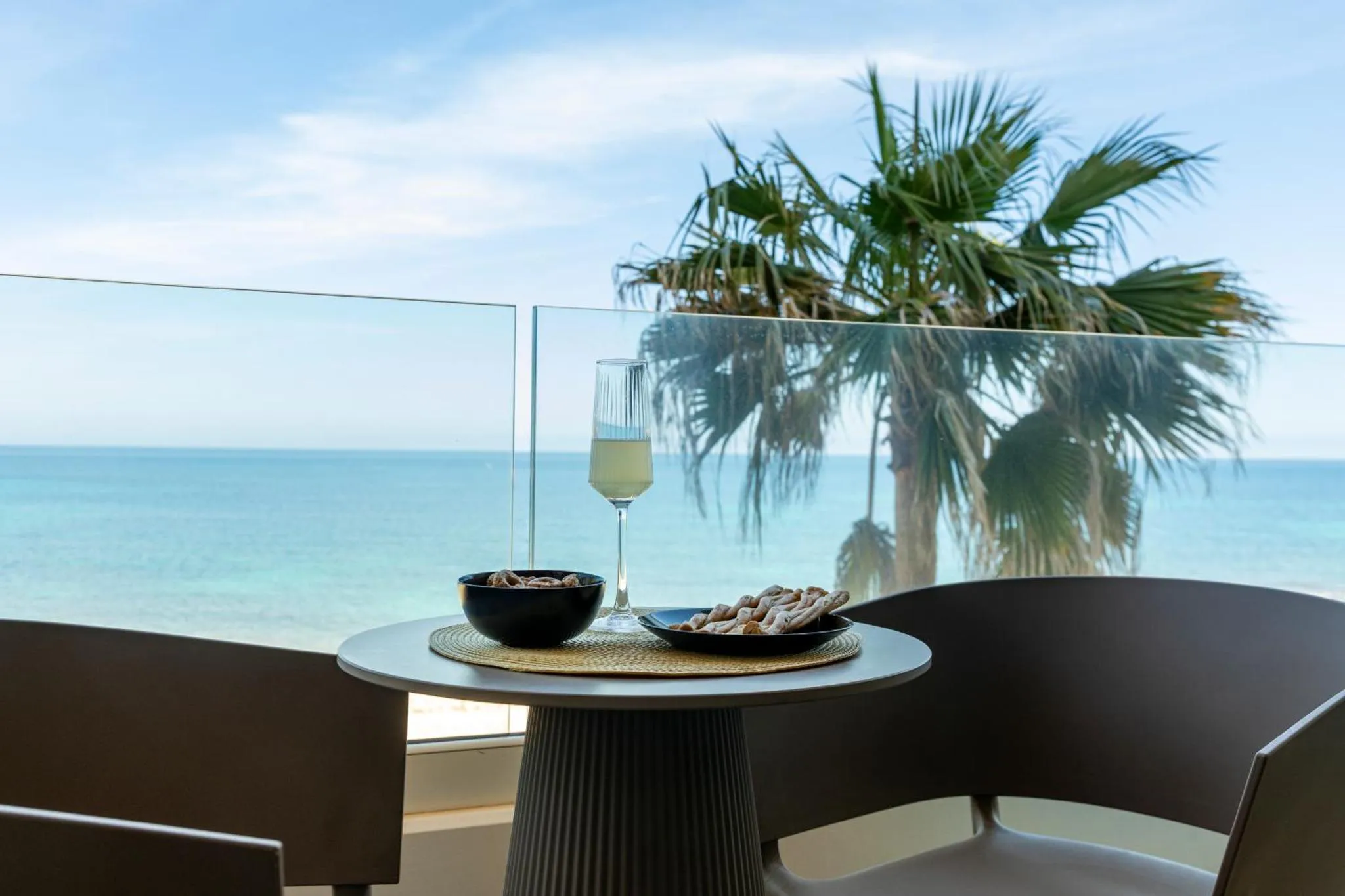 Une table avec des fruits et une boisson sur une terrasse avec vue sur la mer.