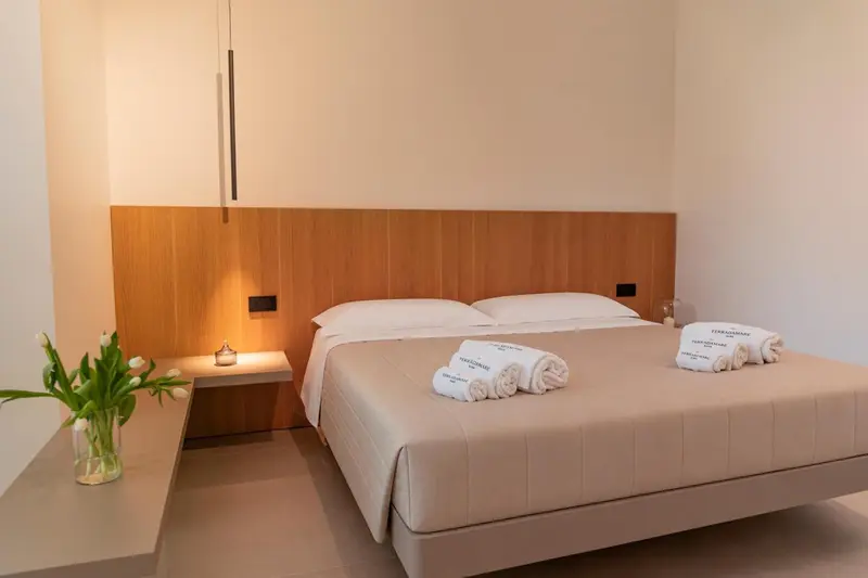 Une chambre lumineuse avec un grand lit recouvert d'une courtepointe et de coussins.